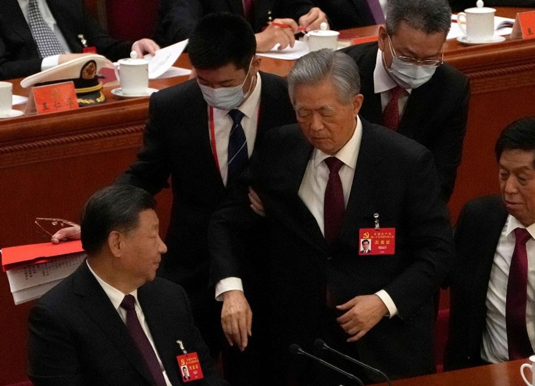 Hu Jintao is escorted from the closing ceremony of the CCP Congress